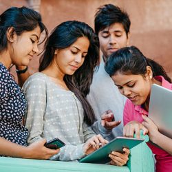 Pretty Smiling Young Indian Students with Laptop and tablet computer Looking at Camera